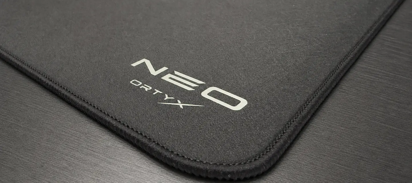 The ORTYX NEO mousepad, close up on its stitched corner and silver NEO logo